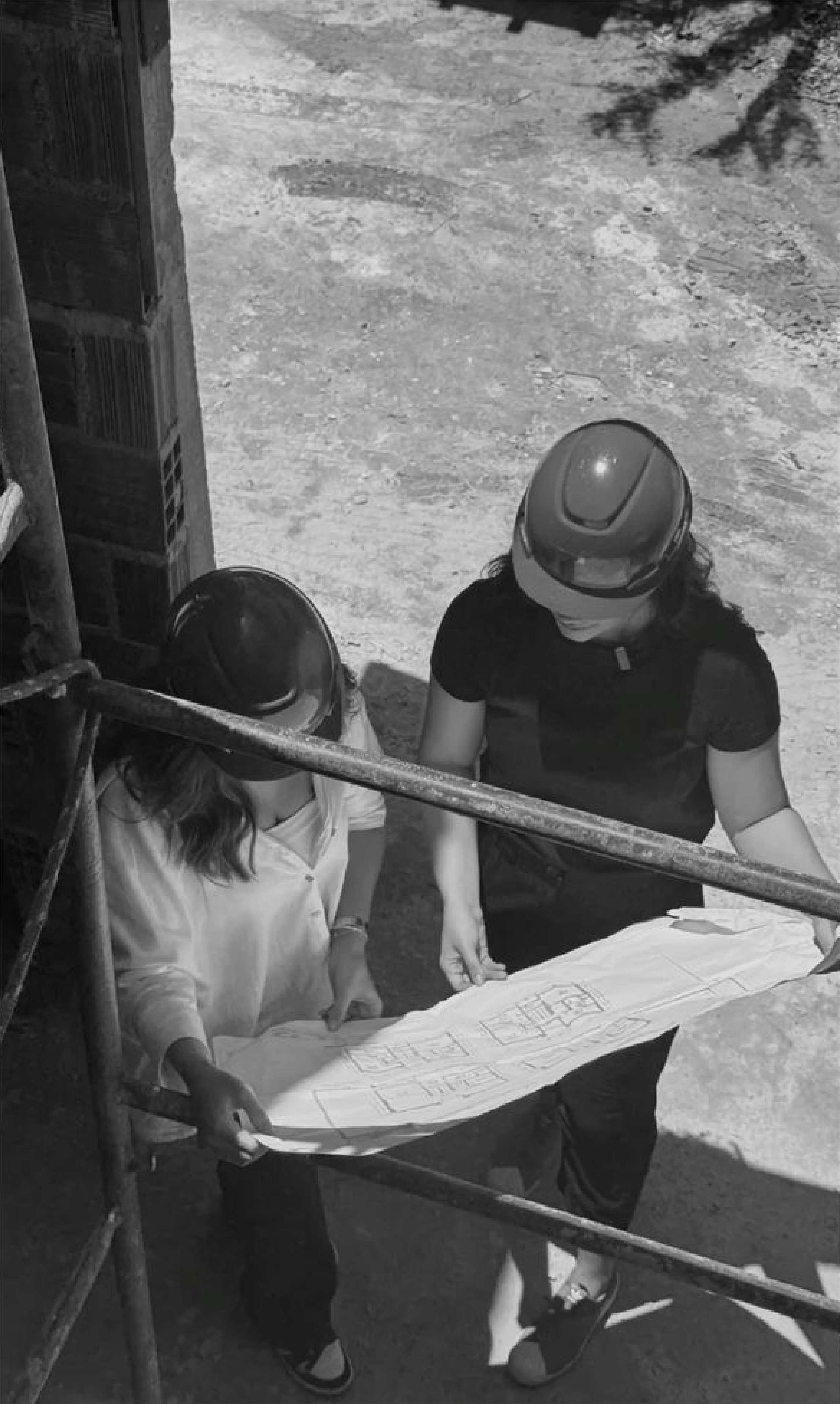 Dos personas con casco leyendo un plano, vistas desde arriba